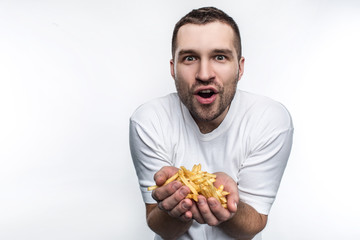 This guy likes fatning junk food very much. He is holding a lot of french fries in his hands. Man can't wait to eat it. Isolated on white background.