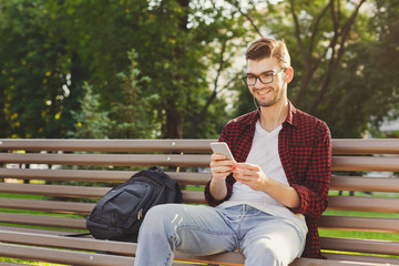 Fototapeta premium Happy young man using smartphone outdoors