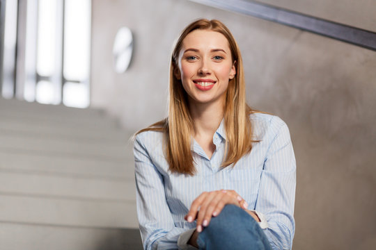people, business and education concept - happy smiling woman or student sitting on stairs