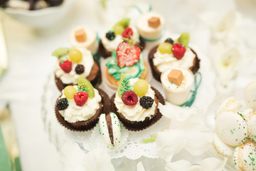 Delicious and tasty dessert table with cupcakes shots at reception closeup