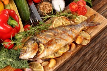 Grilled dorada with vegetables on old wooden background with space for text