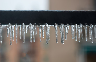 Close Up of icicles hanging on iron row of balcony in house, Ice coated background.
