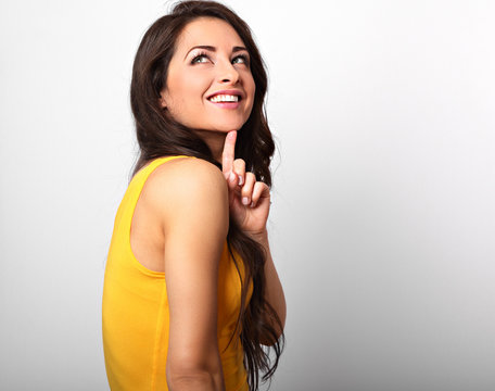 Beautiful positive happy long hairstyle woman in yellow shirt with toothy smile looking up on white background