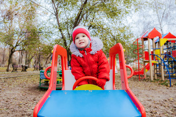 baby sitting at the wheel of a children's car on the playground