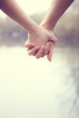 man and woman hands holding on a lake