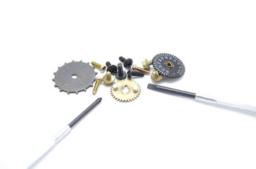 Gears, screws and screwdriver on white background closeup