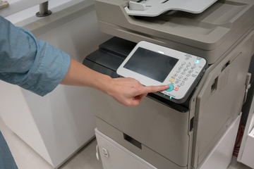 Woman's hands pressing button on copy machine in office