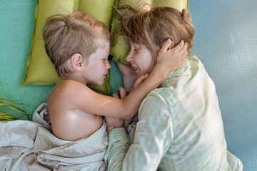 Cute little boy resting with his mom and lying outdoor on mat