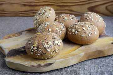 the buns sprinkled sunflower seeds sesame and oat flakes are on a wooden surface. These are bakery culinary products.They are made of rye flour.