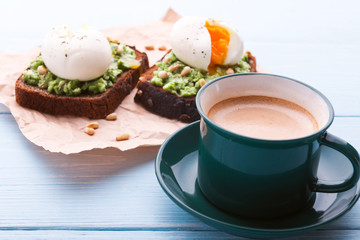breakfast bruschetta with avocado and spinach and poached egg. with a cup of coffee