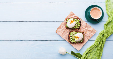 breakfast bruschetta with avocado and spinach and poached egg. with a cup of coffee