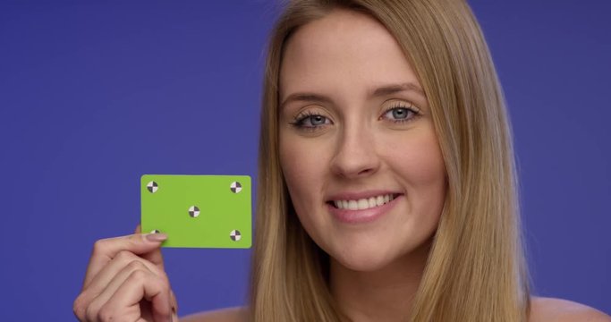 Close Portrait of a Woman holding a blank Card and giving a stunning Smile to the Camera