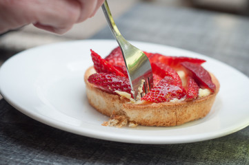 closeup of woman eating strawberry tart in outdoor