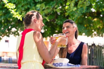 Women in beergarden having refreshment sitting under tree in the shade as it is hot