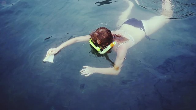 Young woman snorkeling in mask feeding fish with piece of bread in the sea. slow motion. 1920x1080