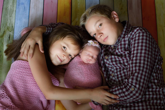 Closeup Portrait Of Three Cheerful Kids Lying Down At Home, Newborn Baby With Brother And Sister, Happy Family, Love And Friendship Concept