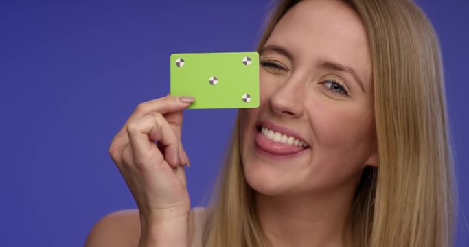 Close Portrait of a beautiful Woman holding a blank credit card and making funny faces