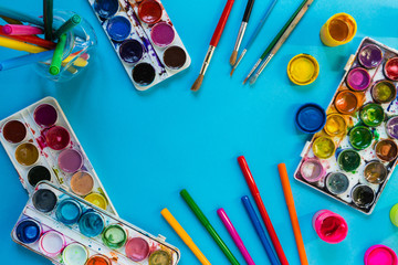 Watercolor paints, artistic brushes, felt-tip pens accessories for an artist long drawing on a blue...