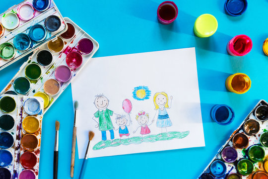 Childrendrawing pencil happy family mom, dad, son, daughter sunny day on the lawn and paint accessories, brush, felters gouache, watercolor on a blue background flat  lay top view from above