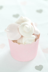 Pink and white meringues in a pink container against a light background, pastel colors, lots of light.