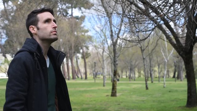 Hombre joven de perfil paseando por el campo observando el cielo y los alrededores