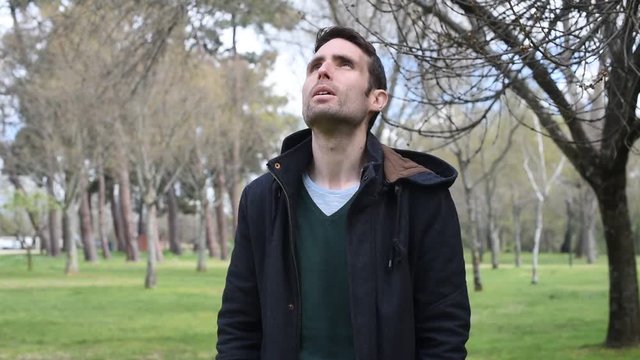 Hombre hombre joven dirigiéndose a cámara mientras pasea por el campo observando el cielo y los alrededores