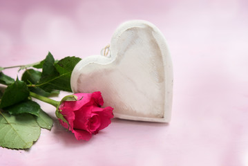 heart of wood and a rose on a pink background, love symbol for valentines or mothers day