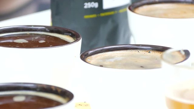 Hands with two spoons remove the foam from the coffee