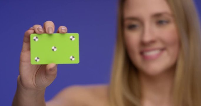 Rack Focus Shot of a beautiful Woman holding a blank Credit Card into the Camera