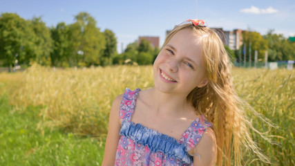 Portrait of a blonde and smiling Russian girl next to the field.