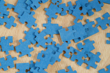 Blue jigsaw puzzle pieces on wooden background