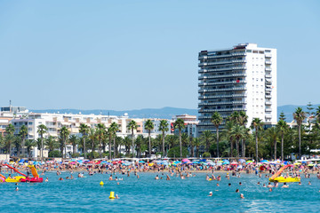 People swim in the Mediterranean sea and relax on the beach.