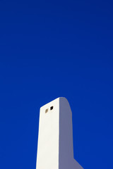 A close up of a white chimney with the blue sky in the background
