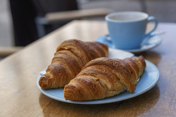 two fresh croissants on a plate closeup as background
