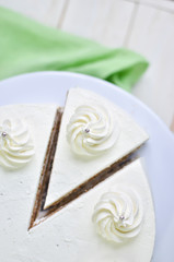 Triangular piece of tender biscuit cake in white cream with cream peaks and silver beads