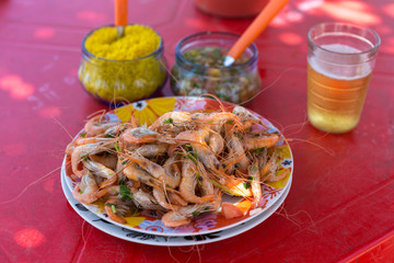 Fried shrimp served with farofa (fried manioc flour), vinaigrette and a glass of beer on red...