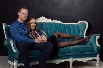 Obraz premium Beautiful enamored young couple in classic clothes sits on a blue sofa with a beautiful old letter