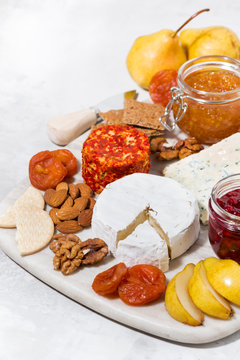 assortment of delicacy cheeses and snacks on board, vertical top view
