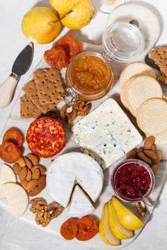 assortment of delicacy cheeses and snacks, vertical top view