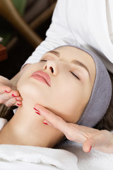 Obraz na płótnie Canvas Beautiful girl doing face massage at the spa salon