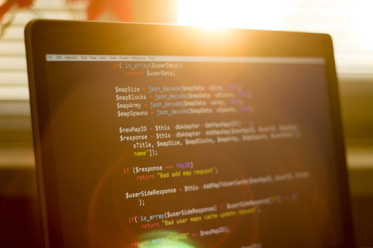 PHP back-end code in sunset rays. Computer programming source code. Abstract screen of web developer. Digital technology modern background.