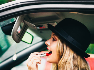 Young woman applying lipstick in car