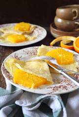Thin soda water pancakes (blinis) with caramelized orange slices for breakfast