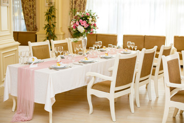 Beautiful setting of wedding party in restaurant. Tables and chairs decorated with flowers and fabrics gently pink in color