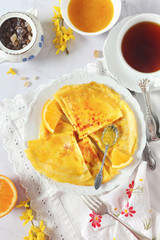 Thin pancakes (blinis) in orange sauce and cup of black tea for breakfast