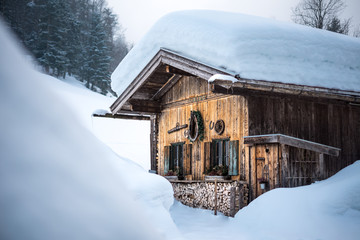 old traditional wooden cabin lodge shack in bavarian alps with lots of snow in winter