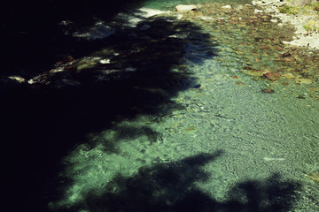 Río de agua azul cristalina con sombras de árboles 