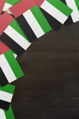 Fototapeta na wymiar United Arab Emirates small flags framing a wood texture background with copy space