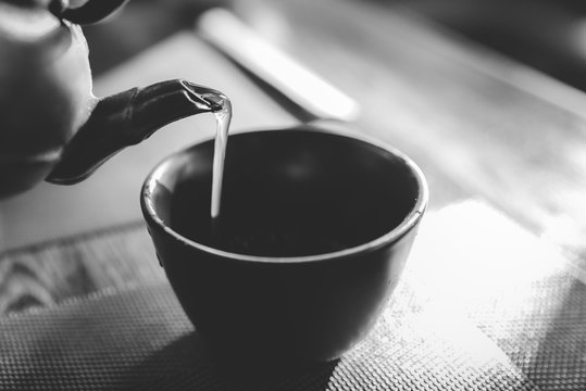 Close Up Pouring A Hot Japanese Green Tea Kettle On An Oriental Style Cup On Table - Natural Light