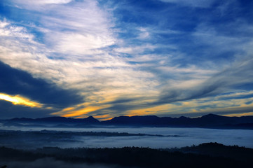 Bright sunrise, the mist in a mountain valley and mountain peaks on horizon.